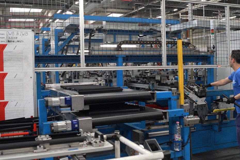 Pracownik obsługujący linię produkcyjną w fabryce części motoryzacyjnych.